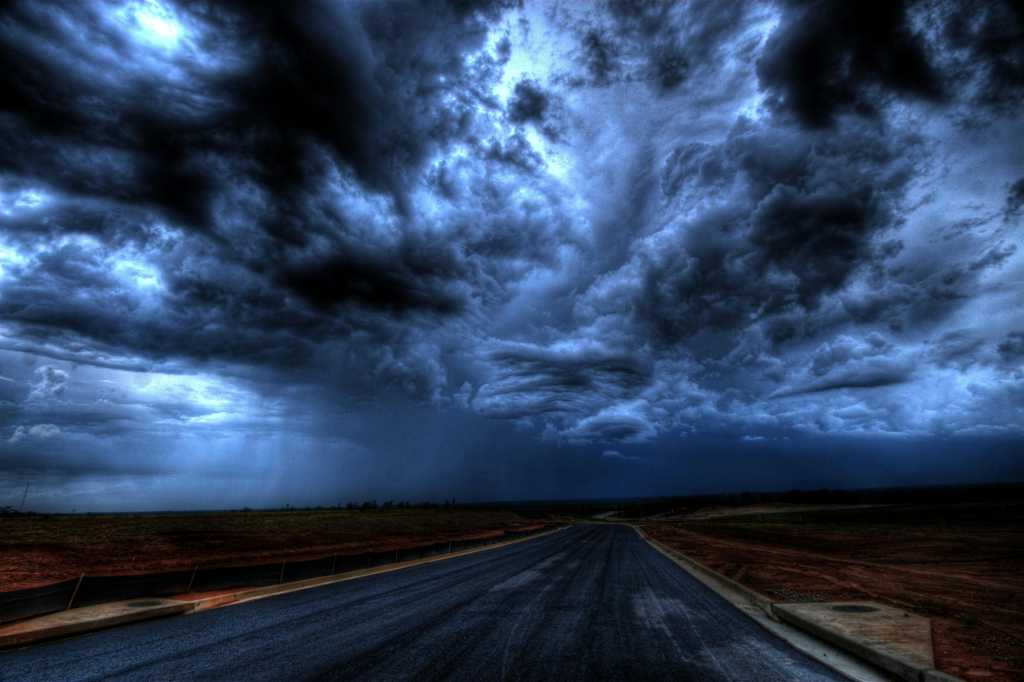 road stretching to horizon under dark ominous cloudy sky