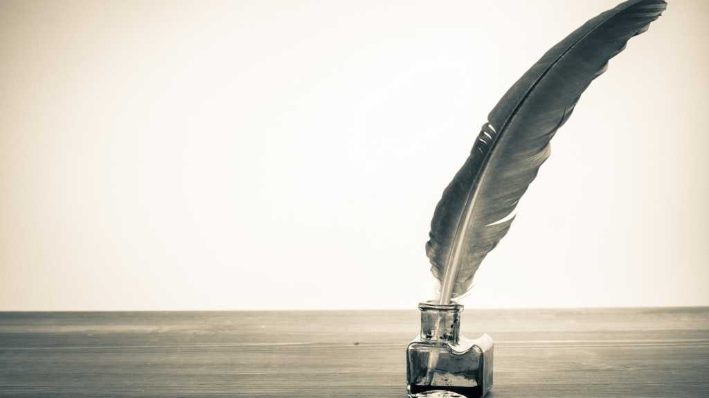 Vintage background with quill pen and inkwell on table