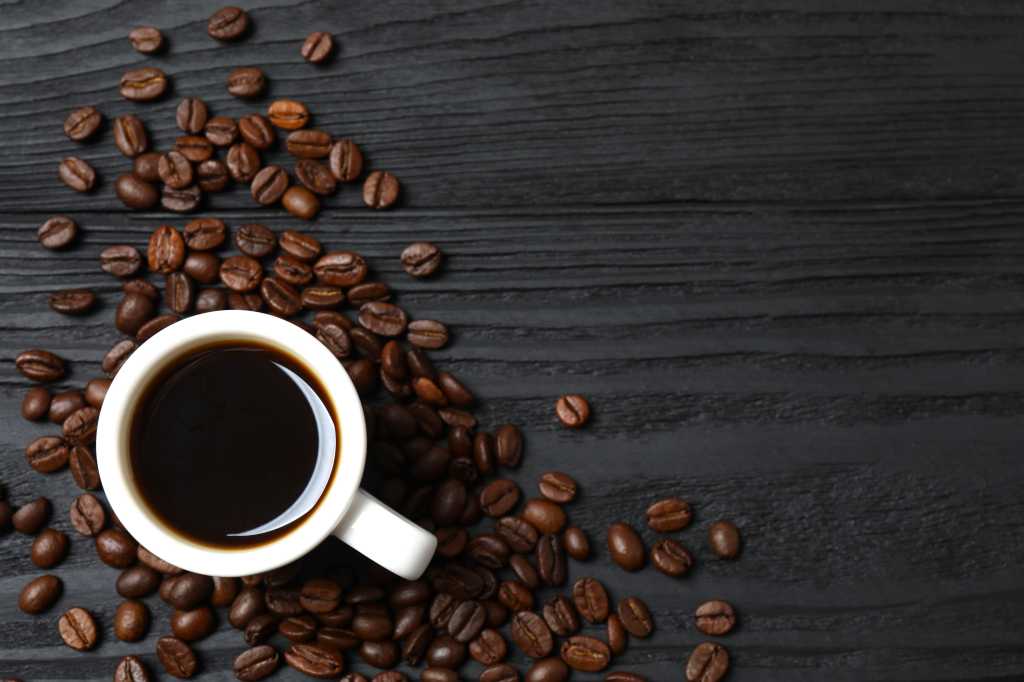 Cup of coffee and fresh coffee beans on wooden background