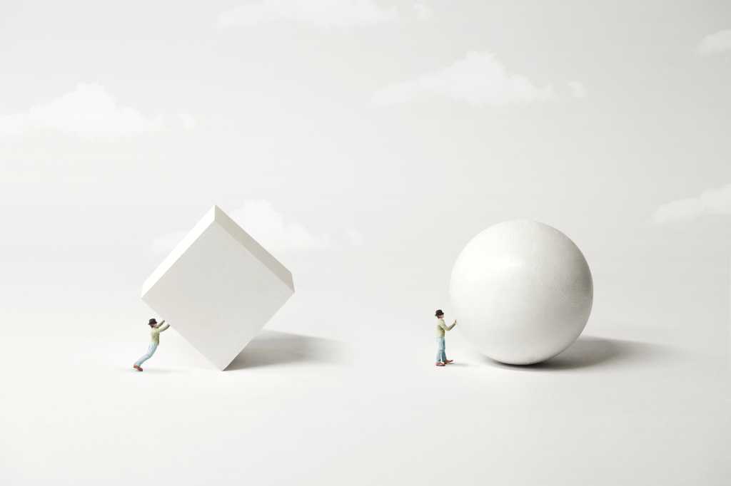 Surreal minimalist conceptual diagram of man pushing pushing block versus man pushing a ball. White objects against a gray background with white clouds. Hard way versus easy way. Evolution of ideas. Technology innovation. .