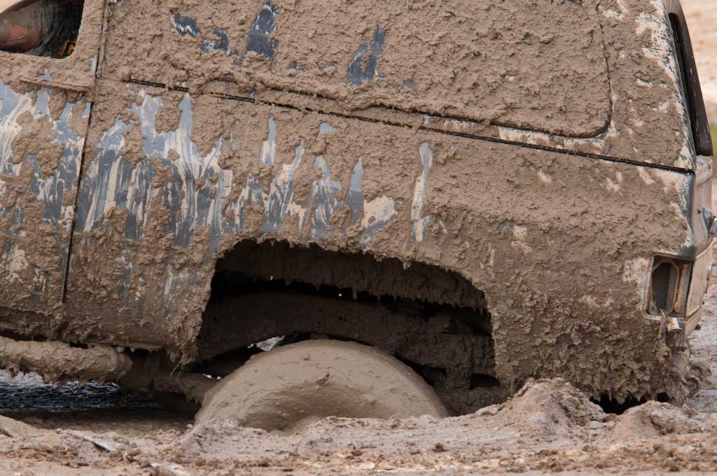 side-angle view of muddy four-wheel drive pickup SUV truck stuck in the mud