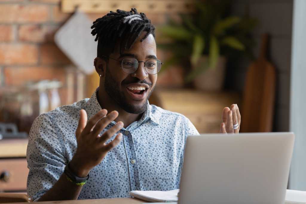 Software developer celebrates in front of open laptop screen. Happy developer, celebration, achievement.