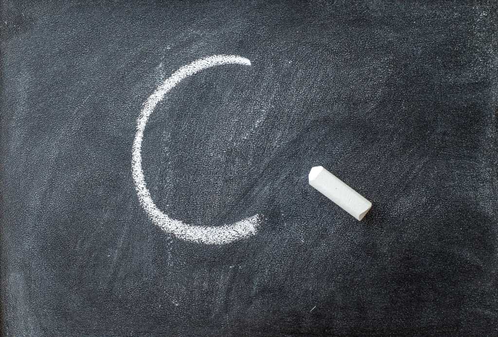 The letter C written on a blackboard with chalk stick.
