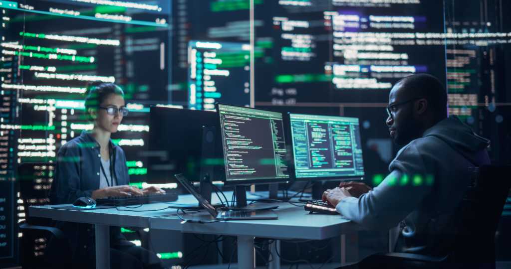 Portrait of Two Diverse Developers Working on Computers, Typing Lines of Code that Appear on Big Screens Surrounding Them. Male and Female Programmers Creating Innovative Software, Fixing Bugs.