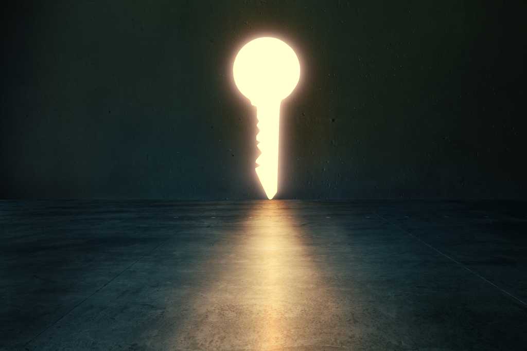 Light glows through key shaped hole in dark empty room. Golden key concept