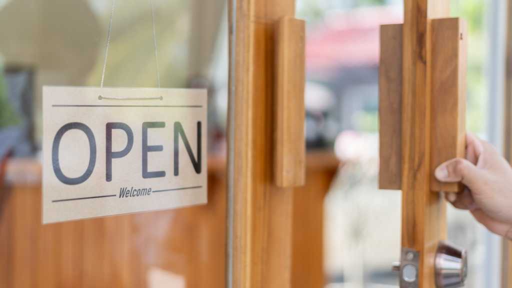 A photograph of a door with a sign reading "OPEN Welcome" hanging in the window.