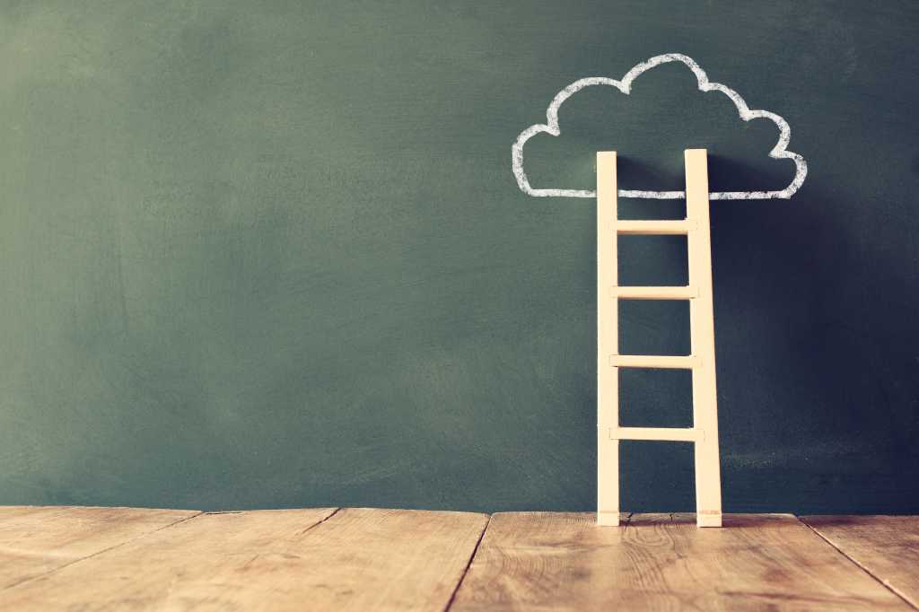 Short wooden ladder on a wooden floor leaning against a cloud drawn in white chalk on a blackboard wall.