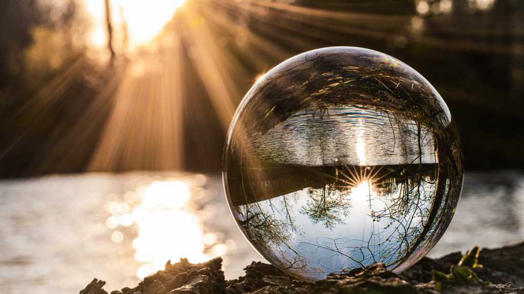 Clear glass crystal ball on brown dried leaves