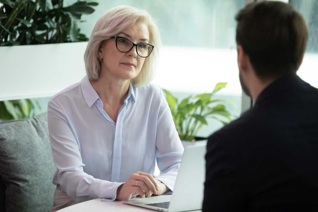 Mature hr manager listen applicant during job interview in office, looking at candidature with skepticism not sure that person is suitable for vacant position, client and bank worker meeting concept