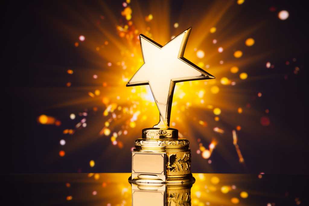 Gold star sits on a pedestal throwing sparks against a dark background.