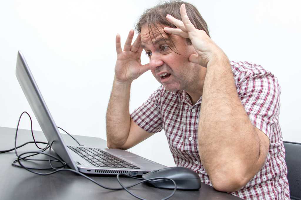 The confused unhappy user is looking at the computer screen. Surprised stressed man looking at laptop. System error on computer.